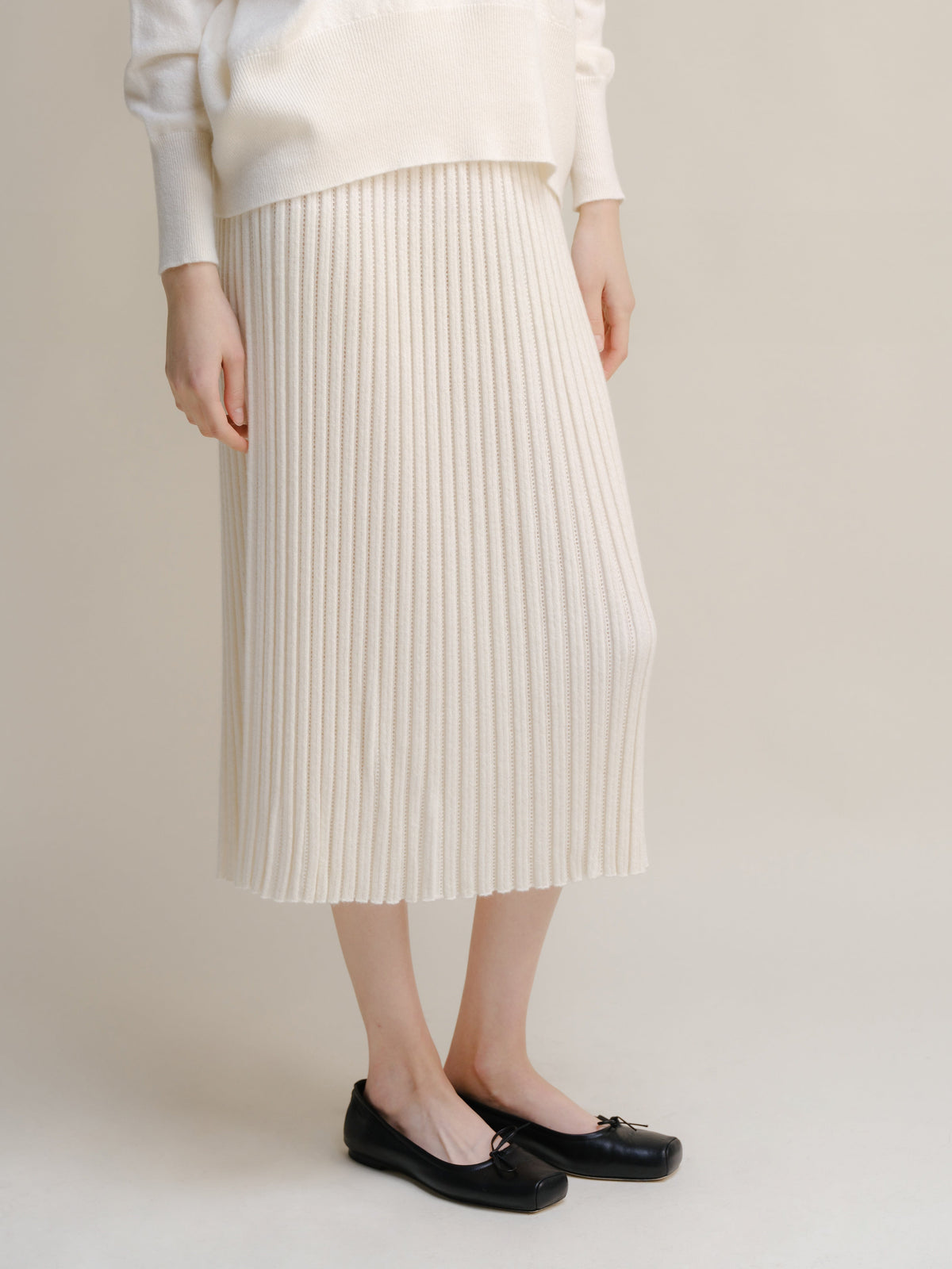 Full view of a cream white cashmere blend knit midi skirt paired with a matching sweater