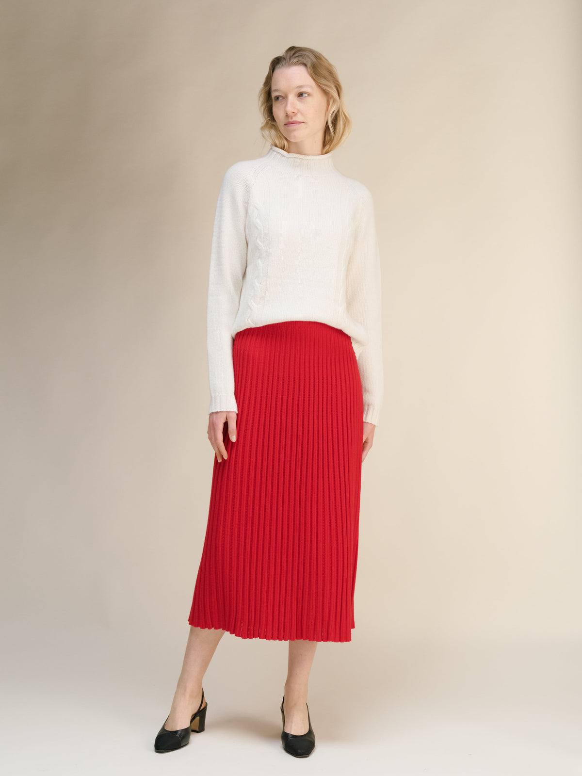 Model wearing a white knit sweater paired with a bright red knit midi skirt with vertical ribbing