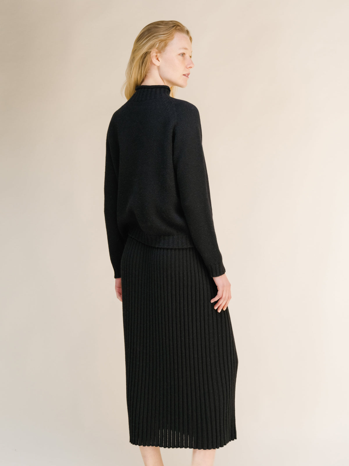 Back view of a model wearing a black cashmere blend perforated 3D-knit skirt.