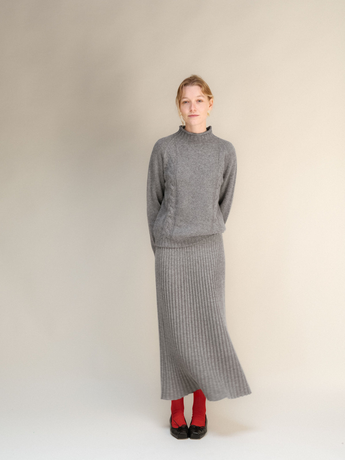 Model wearing gray cashmere blend 3D-knit ribbed maxi skirt with a matching sweater against a neutral backdrop