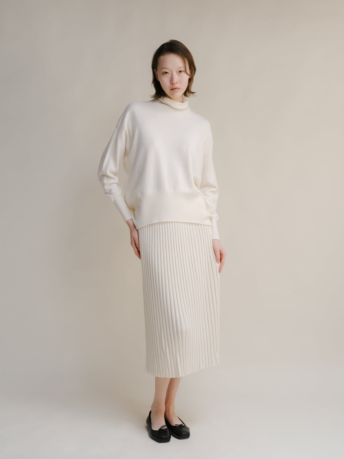 Cream turtleneck knit sweater with a matching ribbed midi skirt.