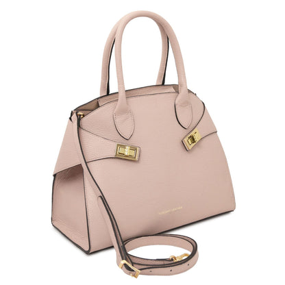 Angled view of pink beige leather tote showing two top handles and a removable crossbody strap with gold hardware