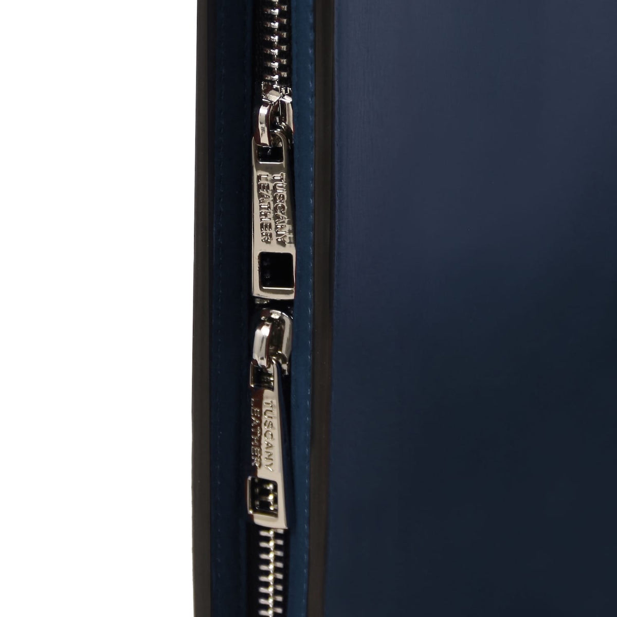 Grande plano of double silver zipper pulls on the azul-marinho leather document case
