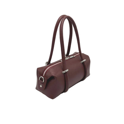 Vista lateral of a burgundy east west handbag sobre fondo blanco