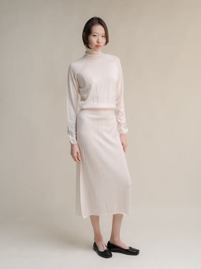 Cream extra fine merino wool 3D knit dress with turtleneck top and matching midi skirt on a model