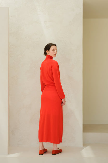 Model wearing bright red merino wool 3D-knit dress with a turtleneck, seen from the back.