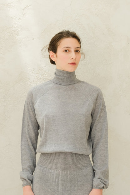 Close up of light grey knit turtleneck top with ribbed waistband and cuffs from the 3D-Knit Merino Wool set.