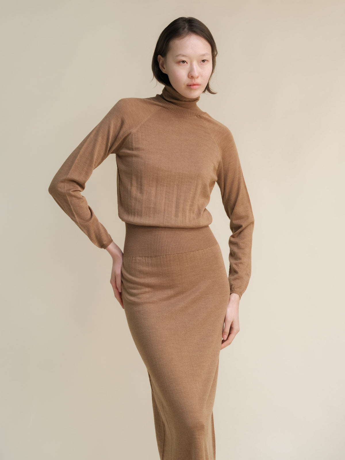Model in beige knit turtleneck and matching midi skirt.
