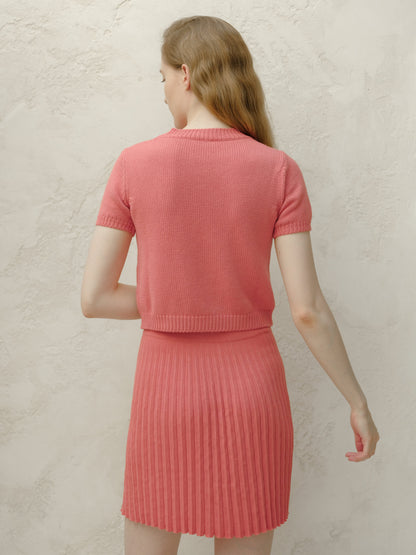 Back view of a modella con a coral rosa knitted top e matching pleated minigonna