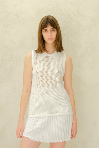 Modella con a bianco mesh sleeveless top con a collarosso neckline e a bianco plissé minigonna.