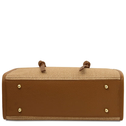 Bottom view of straw effect bag with tan leather base and four gold studs