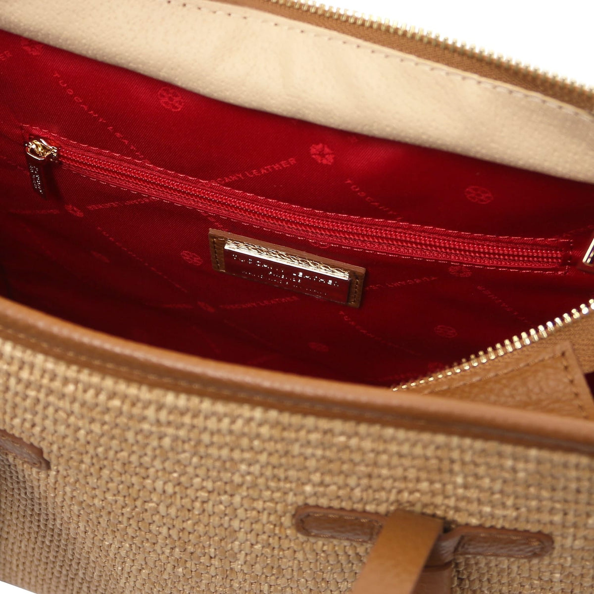 Interior view of the bag with red lining, zip pocket and brand plaque