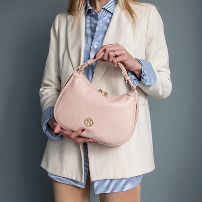 Modelo con a cream blazer holding a pale pink piel suave hobo bag with a textured surface