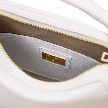 Vista interior of white Hoblò piel suave hobo bag showing light grey lining and a gold plate plaque.