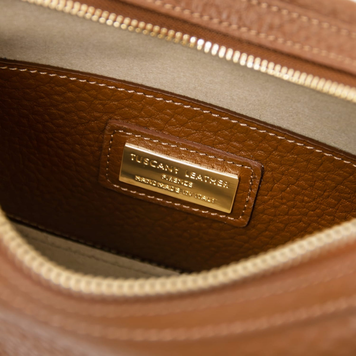 Primer plano of cuero piel granulada interior with a gold metal nameplate stitched on a patch
