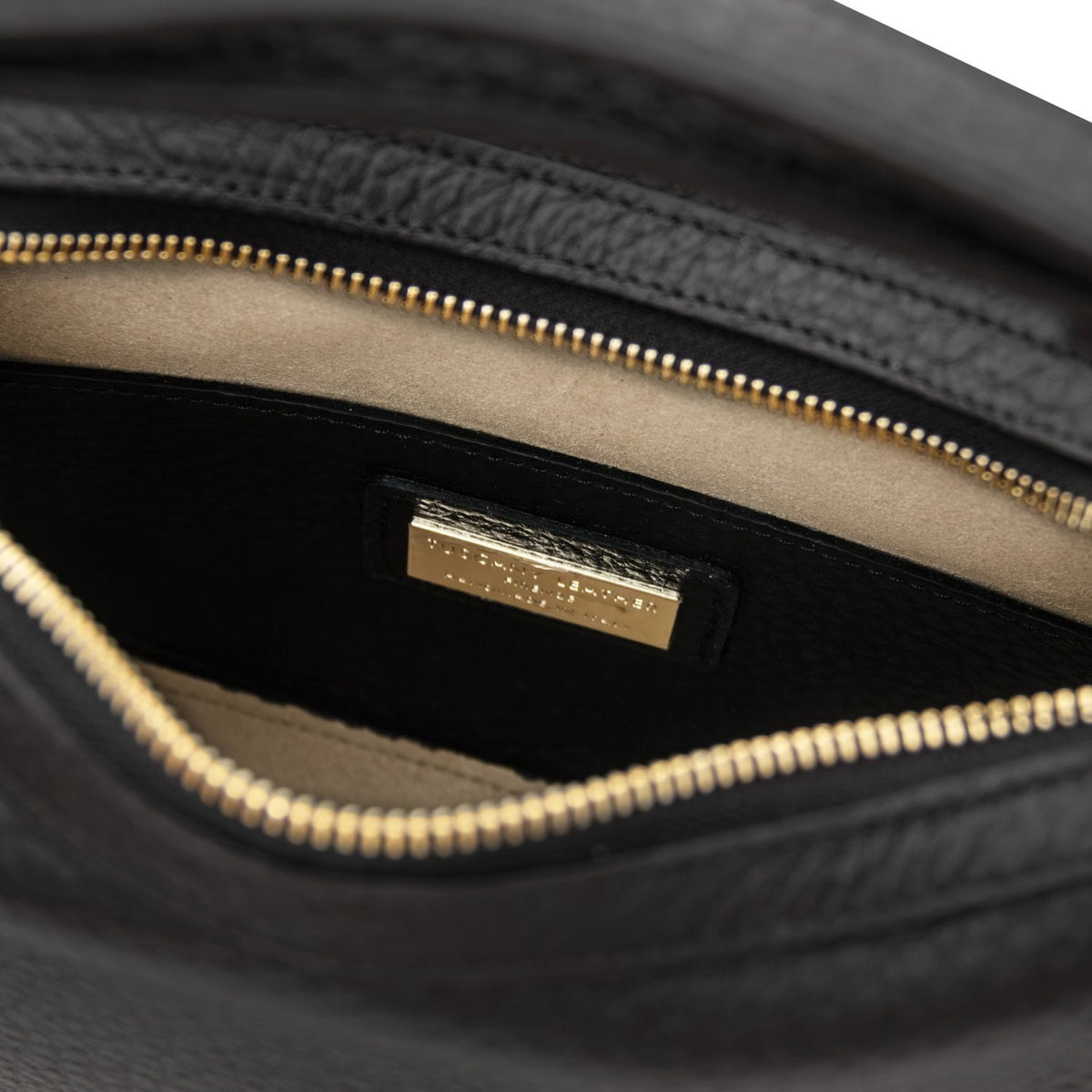 Interior close up of the black Hoblò bag showing the cremallera dorada and a placa de logo dorada on the lining