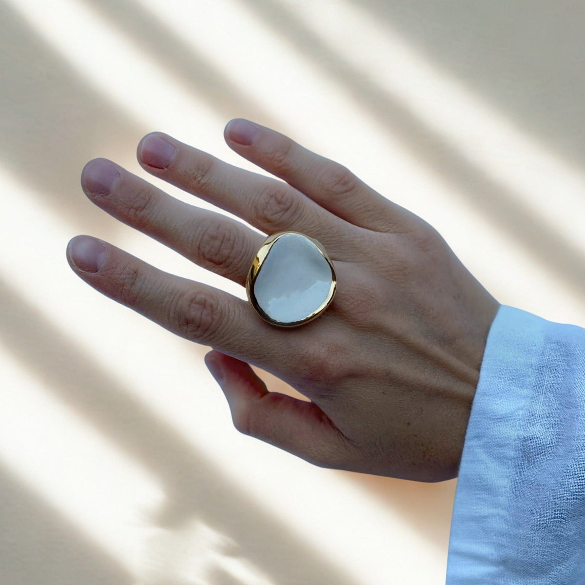 Leda ring worn on finger featuring a white ceramic centerpiece framed in gold