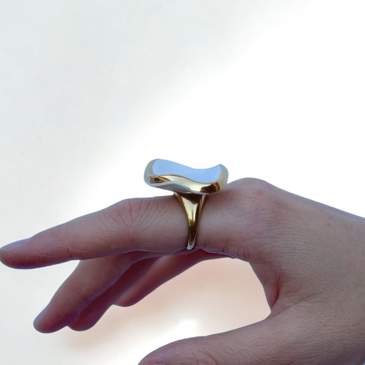 Doré ring with a glossy white irregular ceramic top worn on a finger