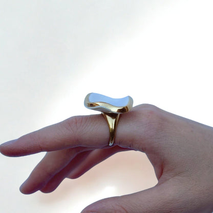 Doré ring with a glossy white irregular ceramic top worn on a finger