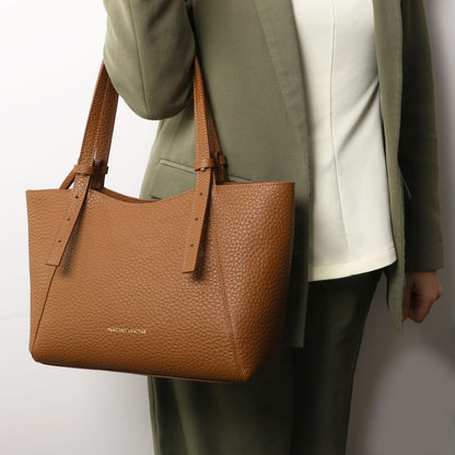 Brown pebbled leather tote with long handles carried by a model in an olive green outfit.