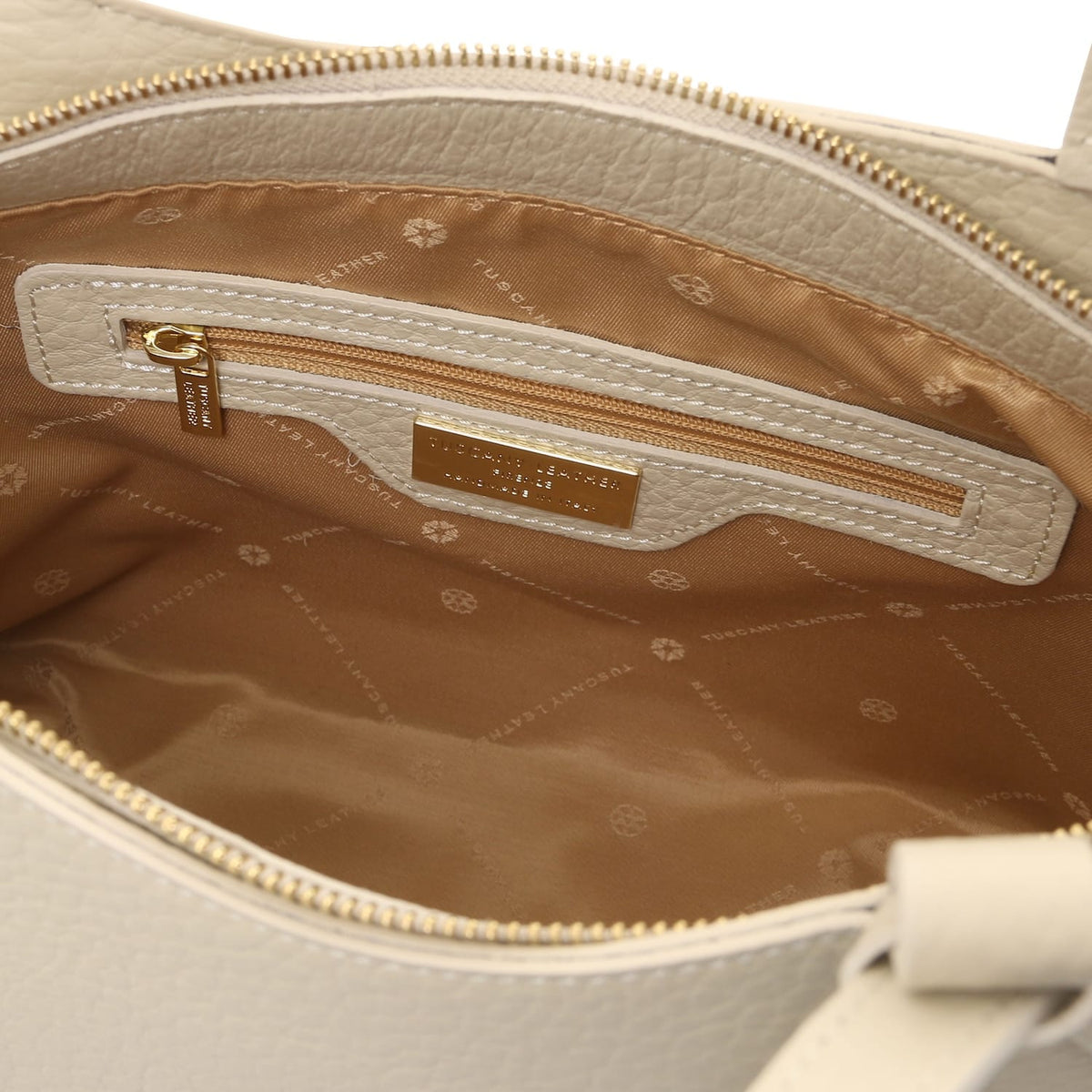 Tan interior of Libra tote showing zipper pocket and gold brand plaque
