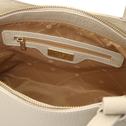 Tan interior of Libra tote showing zipper pocket and gold brand plaque
