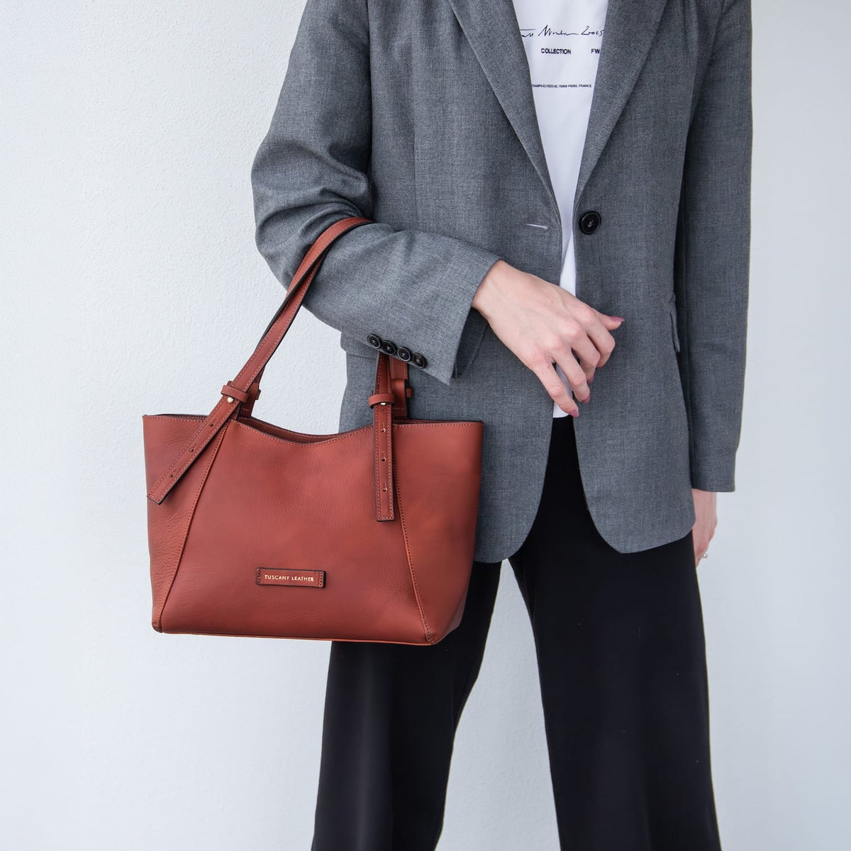 Person holding a brown leather Libra handbag against a plain background