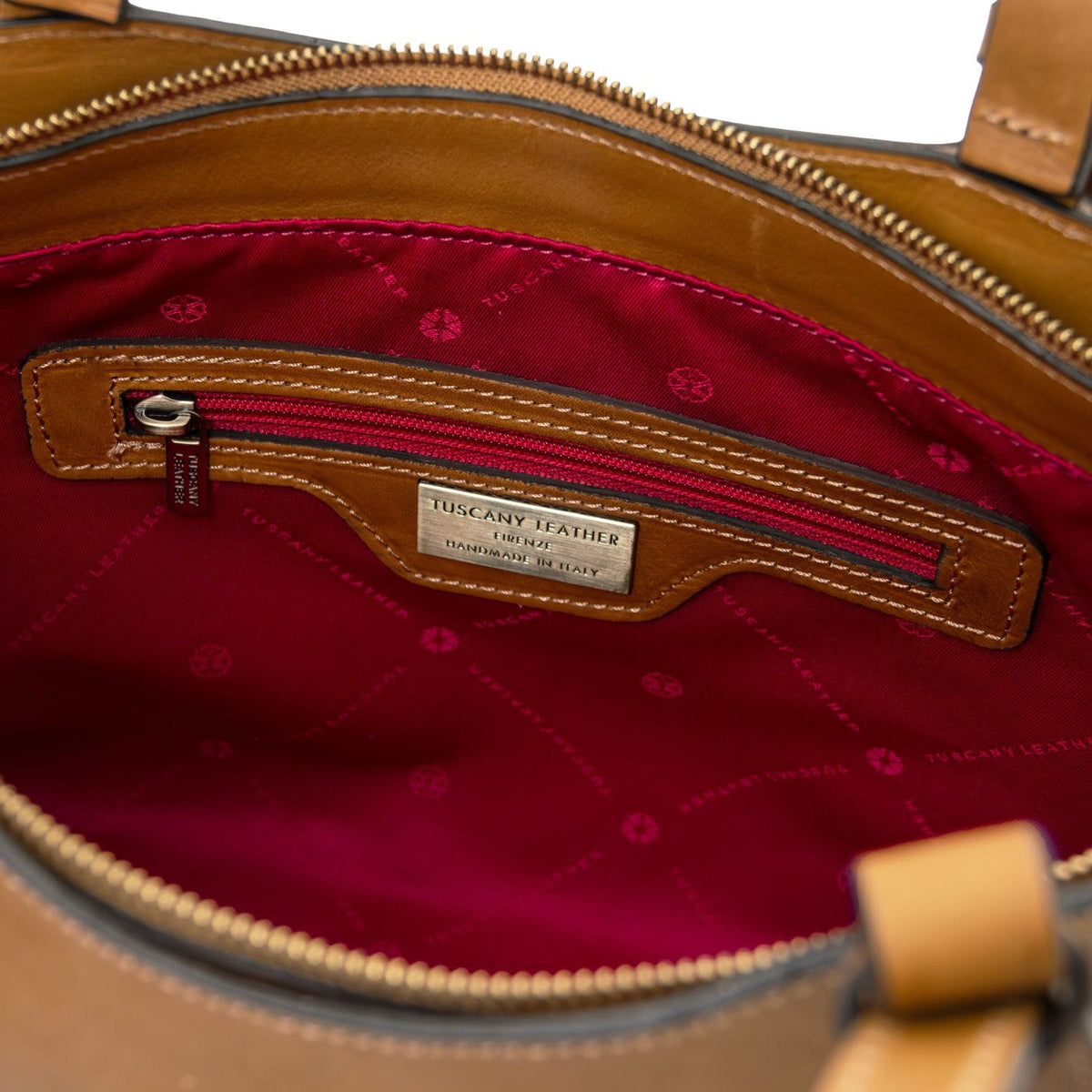 Inside of the Libra tote with red lining and zip pocket and a metal label reading Tuscany Leather handmade in Italy.