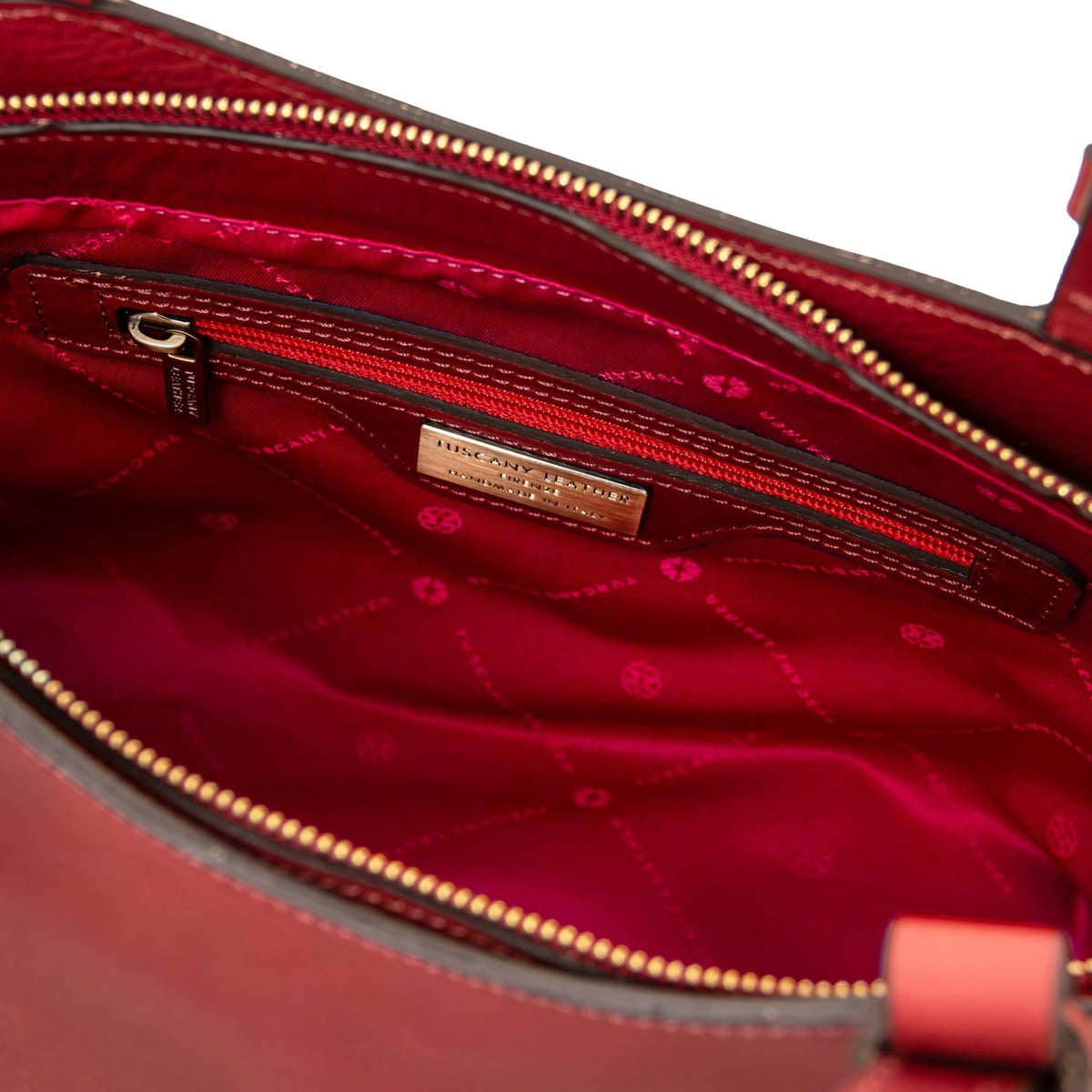 Interior of Libra tote with red lining, zip pocket and metal branding plate