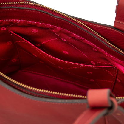 Inside view of a brown leather tote with red lining and stitched pockets.
