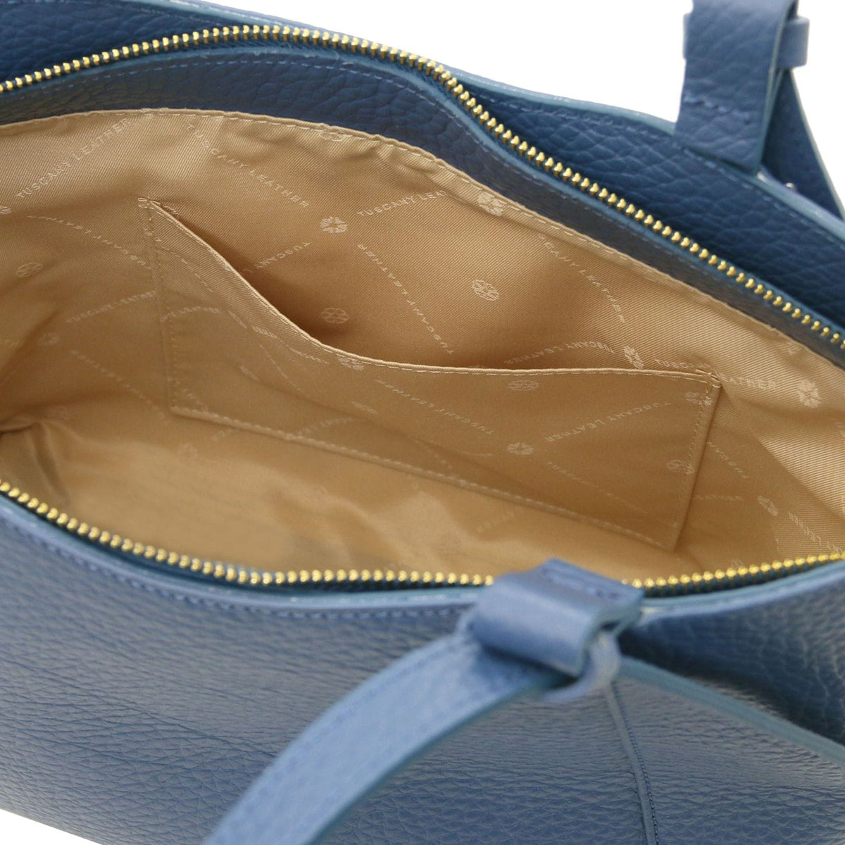 Inside view of a blue Libra long-handle leather tote with beige lining and an interior pocket.