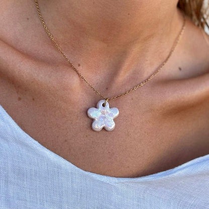 Pearl-pink flower shaped ceramic pendant on a thin gold chain worn at the collarbone