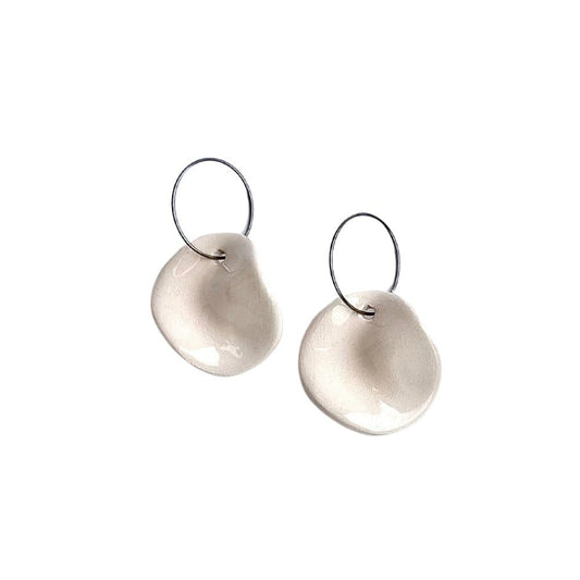 Pair of white ceramic dangle earrings with irregular circular discs on silver hooks against a white background