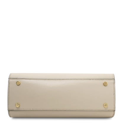 Bottom view of Maisy leather top handle bag in smooth beige leather with four gold studs.