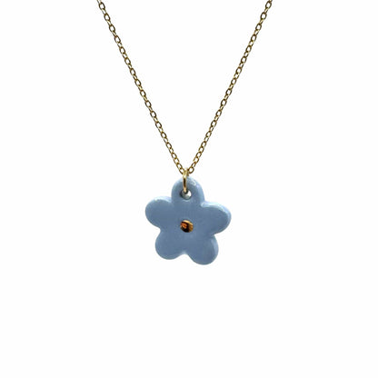 Blu flower ceramic pendant on a gold chain against a bianco background