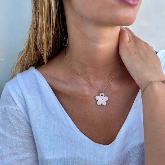 Margherita rosa floral ceramic necklace con a delicate gold chain resting at the collarbone.