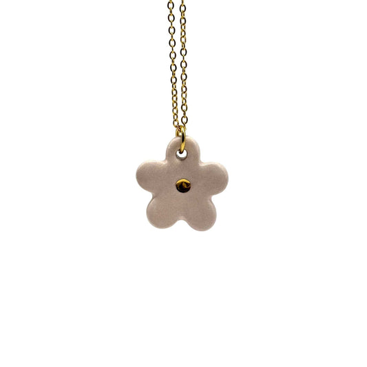 Hecrafted rosa ceramic flower pendant con a gold chain against a bianco background.