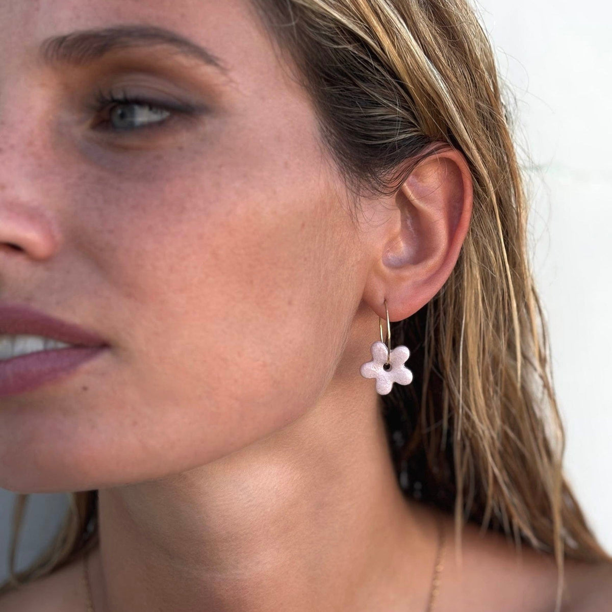 Rose floral ceramic dangle earring on a slender gold hoop porté par un mannequin