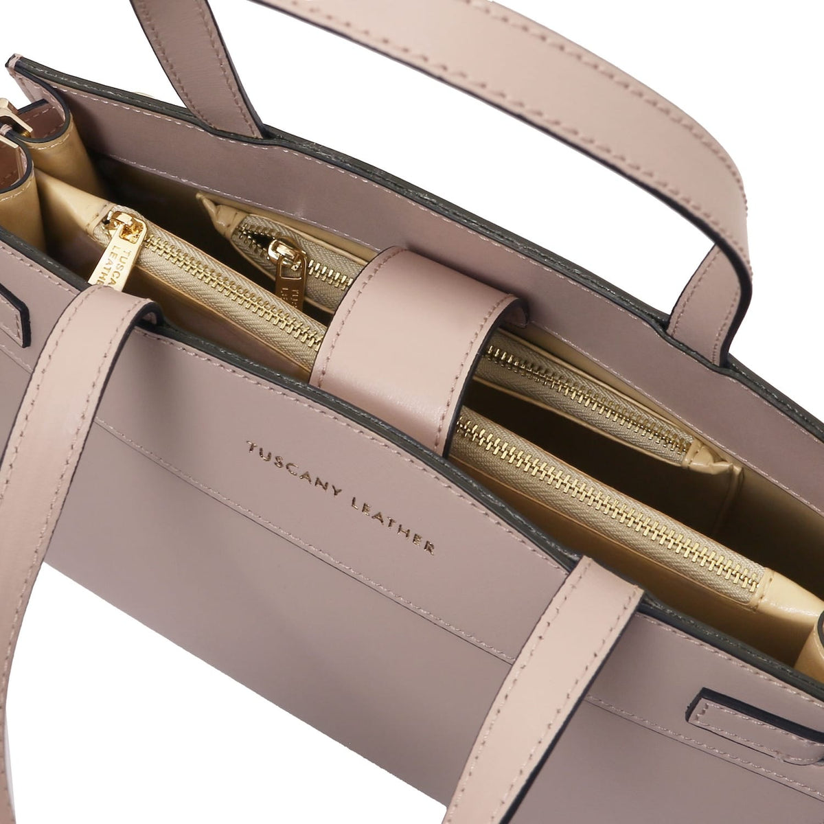 Interior primer plano of the Musa handbag with multiple bolsillo con cremalleras and herrajes dorados.