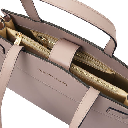 Interior primer plano of the Musa handbag with multiple bolsillo con cremalleras and herrajes dorados.