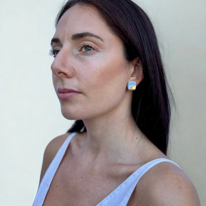 Light blue square ceramic earring with a gold accent worn on the ear