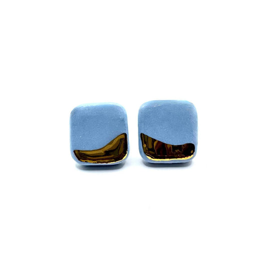 Square light blue ceramic earrings with a gold curved bottom edge.