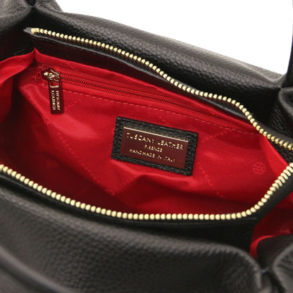Open top of black Nora soft leather bag showing red lining, gold zipper, and brand label inside.