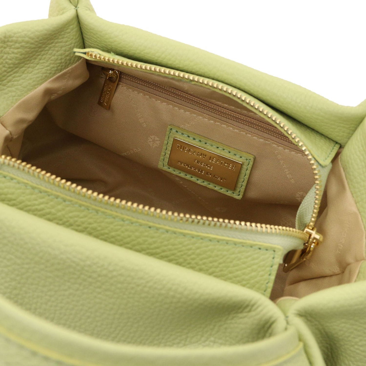 Open view of soft green leather handbag showing beige fabric interior lining and zippered inner pocket with gold zipper pull.