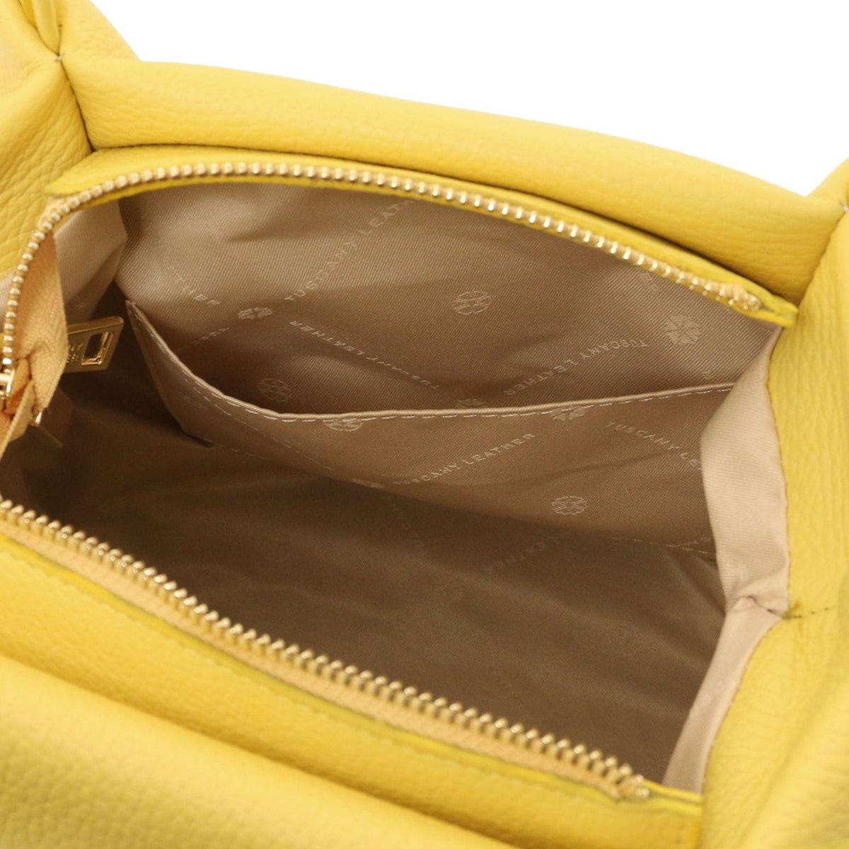 Interior view of yellow soft leather handbag showing beige fabric lining with logo print and inner slip pocket.