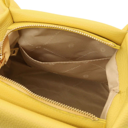 Interior view of yellow soft leather handbag showing beige fabric lining with logo print and inner slip pocket.