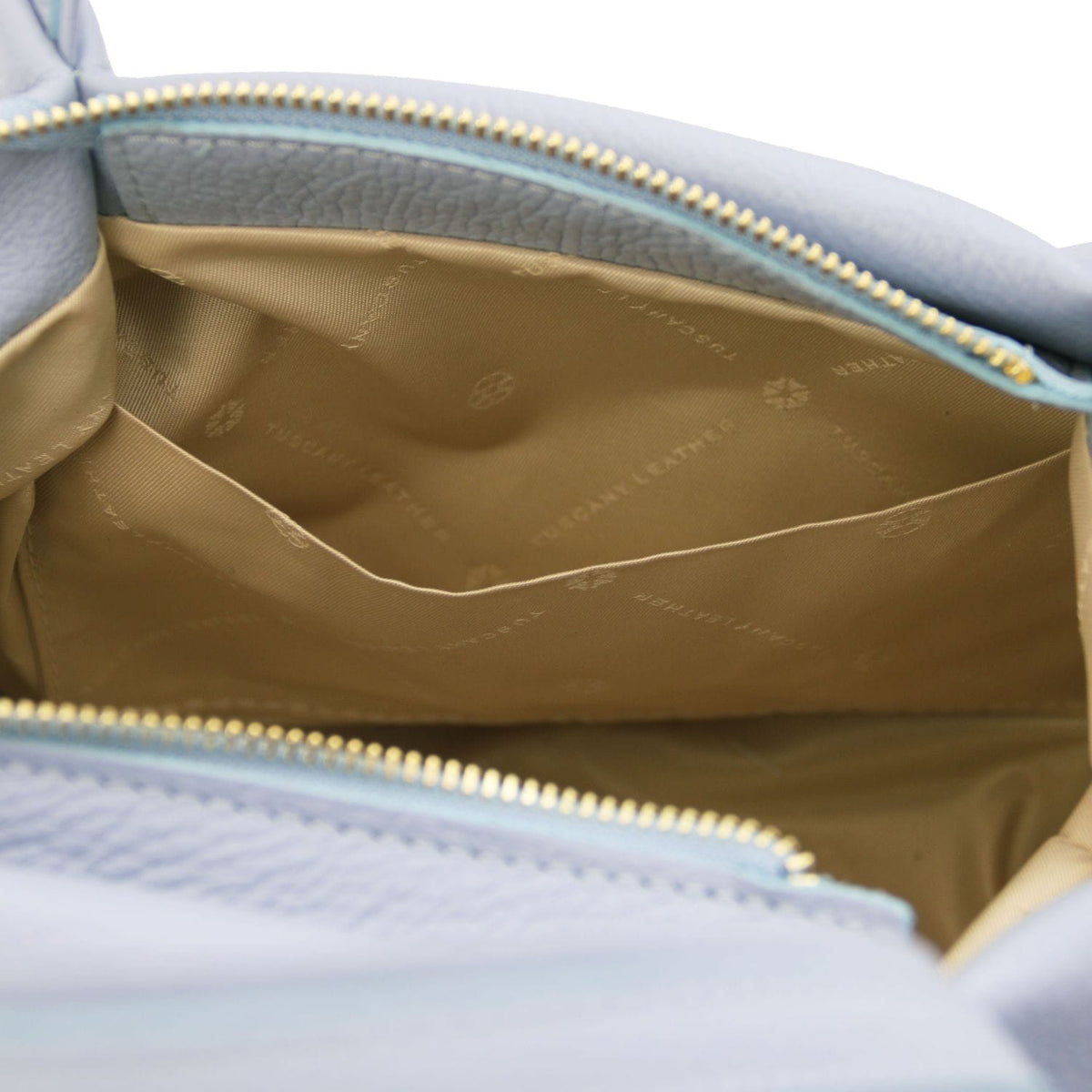 Inside view of the light blue Nora handbag showing tan lining and a back zip pocket along the top edge