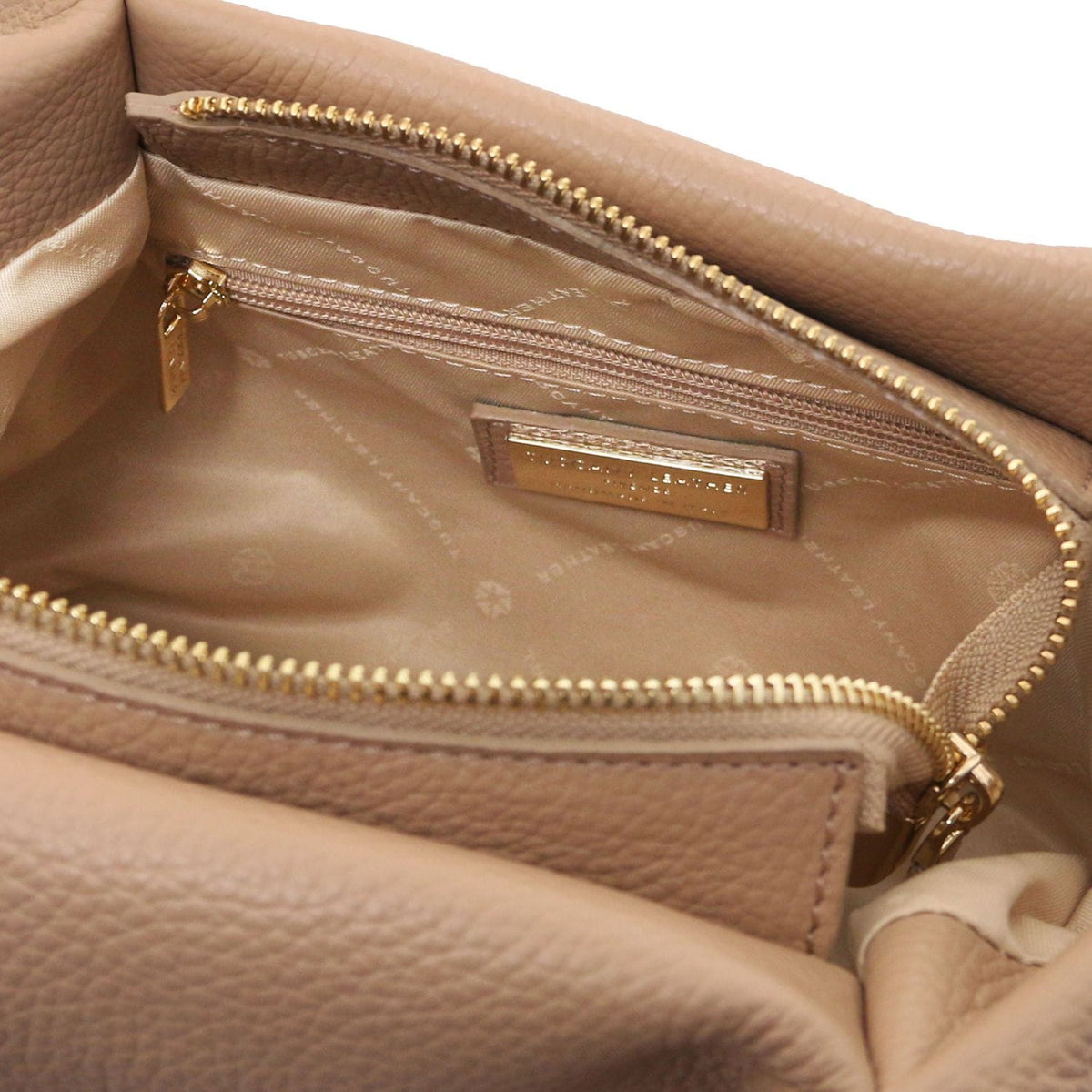 Inside view of beige Nora soft leather handbag showing a zip pocket and gold brand plaque.