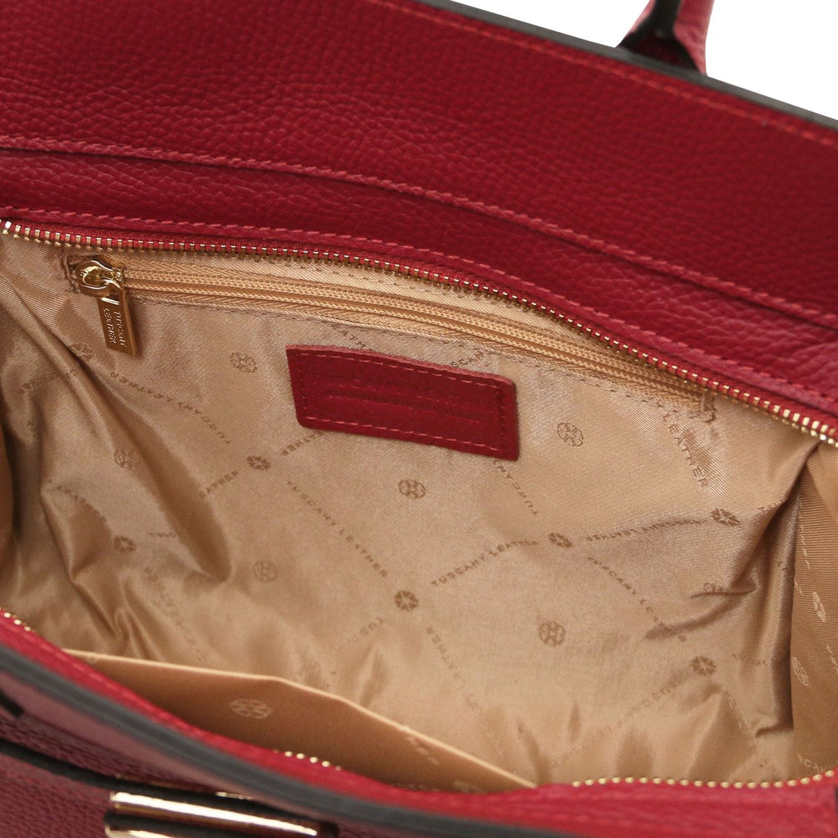 Abierto red leather tote with beige forro con estampado de logo and a cremallera dorada pocket inside.