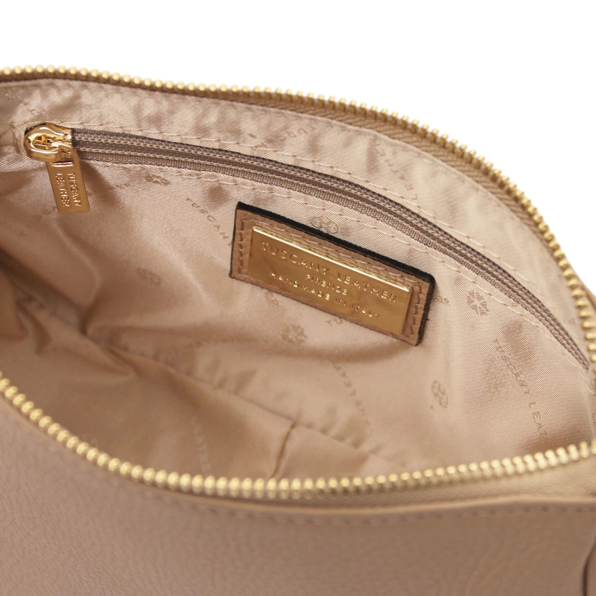 Interior view of Parfait leather clutch with zip pocket and gold brand plaque on beige lining.